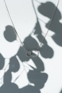 silver necklace on white surface with shadow
